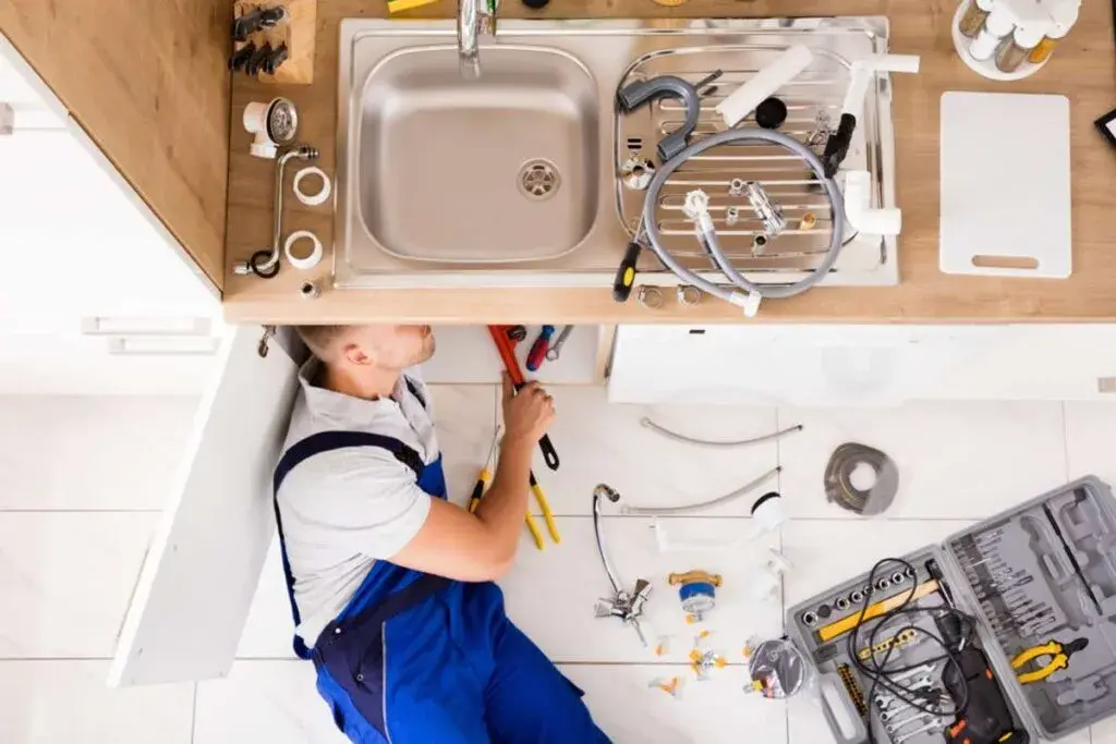A professional plumber working under a sink Seattle property management concept